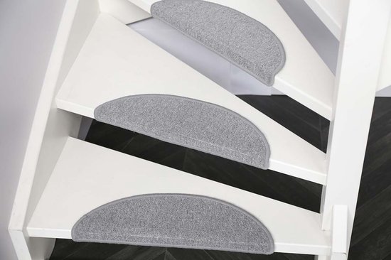 Drie halfronde grijze trapmatten op witte traptreden, close-up.