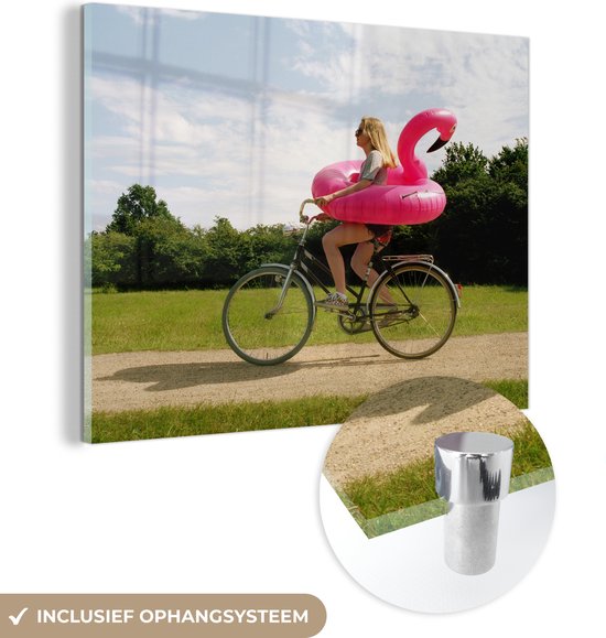MuchoWow® Glasschilderij 160x120 cm - Schilderij acrylglas - Vrouw fietsend met een flamingo zwemband om haar heen - Foto op glas - Schilderijen