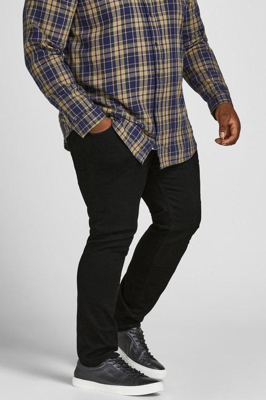 Man met geruite blouse en zwarte jeans, zijaanzicht.