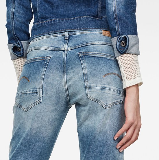 Detail achterkant van lichtblauwe G-Star jeans met zakken en oranje stiksels.
