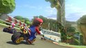 Mario racet op een kartbaan met veel groen. De baan is omgeven door bloemen en heuvels.