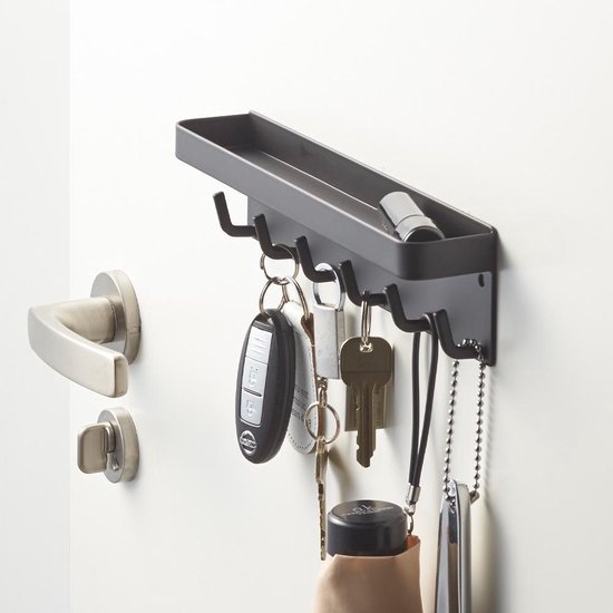 Zwart sleutelrek met zes haken, een sleutelbos, opvouwbare paraplu en een accessoire.