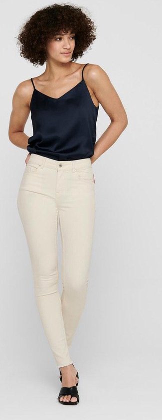 Model met een navy top en beige skinny jeans met rafelige zoom.