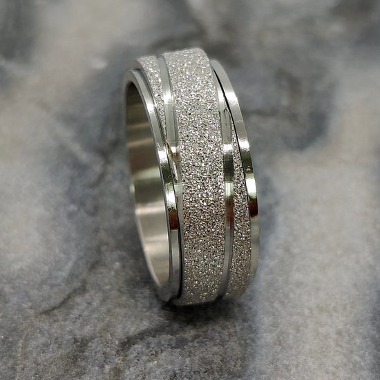 Zilverkleurige ring met een glinsterende, gestreepte band, gedraaid op een marmeren achtergrond.