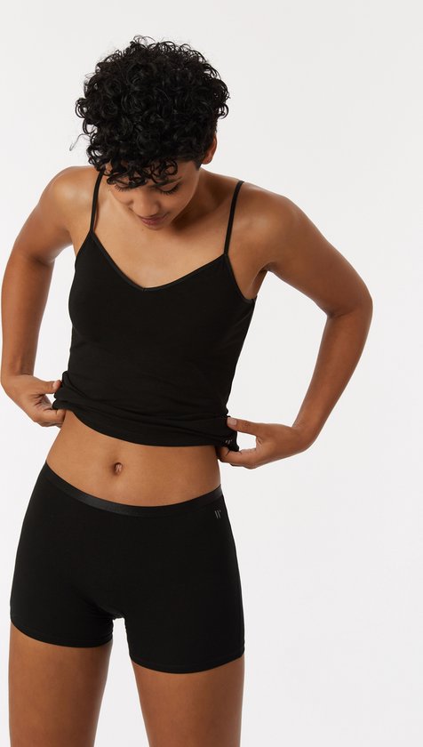 Mannequin portant un débardeur noir et un short, regardant la ceinture, fond blanc.