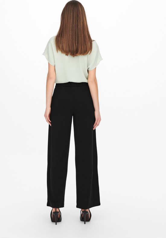 Zwarte wijde broek, gezien vanaf de achterkant, gedragen met een lichtgroene top.