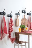 Rood-witte keukenhanddoeken met landelijke print en ruitenpatroon, hangend aan haken.