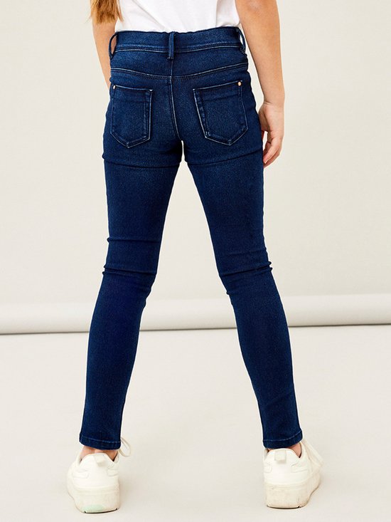 Model draagt een donkerblauwe skinny jeans, achterkant zichtbaar.