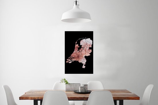 Affiche des Pays-Bas en teintes rose délavé avec bordure noire, suspendue à un mur blanc au-dessus d'une table en bois.