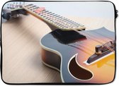 Laptophoes 14 inch - Een elektrische gitaar op een houten vloer - Laptop sleeve - Binnenmaat 34x23,5 cm - Zwarte achterkant
