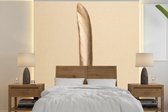 Behang - Fotobehang Goud geverfde veer op een gouden achtergrond - Breedte 220 cm x hoogte 220 cm