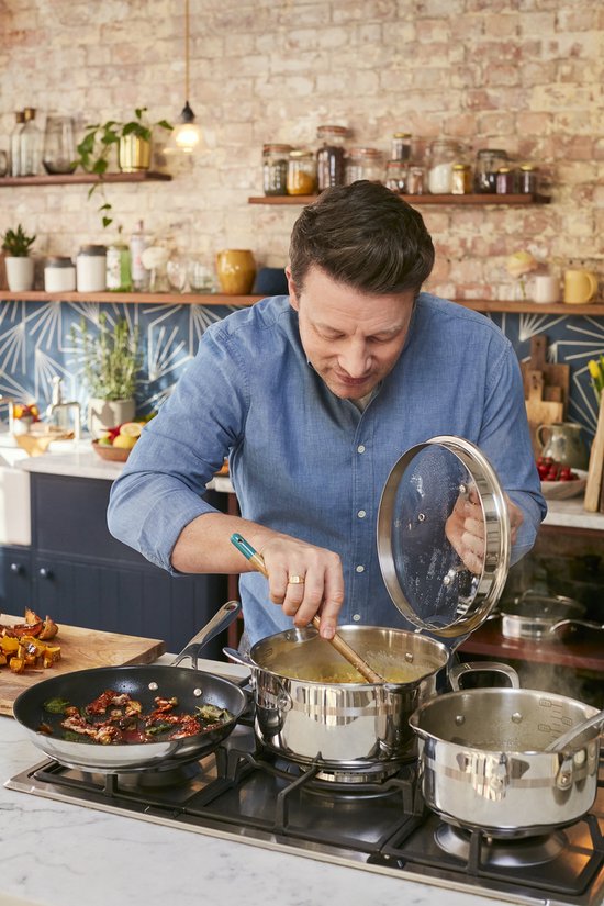 Jamie Oliver roert in een kookpot boven een gasfornuis, met een koekenpan ernaast.