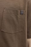 Detail van een bruin t-shirt met borstzakje en Jack & Jones label.