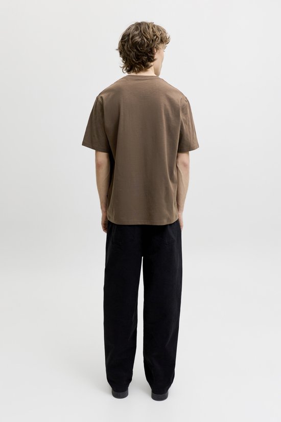 Man van achteren gezien in een effen bruin t-shirt met korte mouwen en zwarte broek.