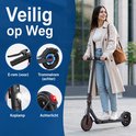 Vrouw rijdt op een zwarte elektrische step met rode accenten, met details van koplamp en achterlicht.