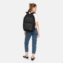 Sac à dos Eastpak noir avec compartiment pour ordinateur portable, porté par une femme en jean bleu et t-shirt blanc.