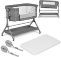 Grijze co-sleeper met mand, matras, en bevestigingsriemen. Twee weergaven van de co-sleeper en de accessoires.