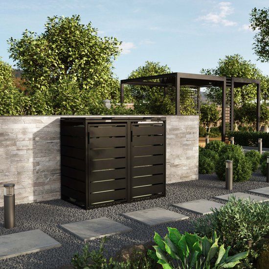 Zwarte containerombouw met horizontale lamellen naast een gemetselde muur.