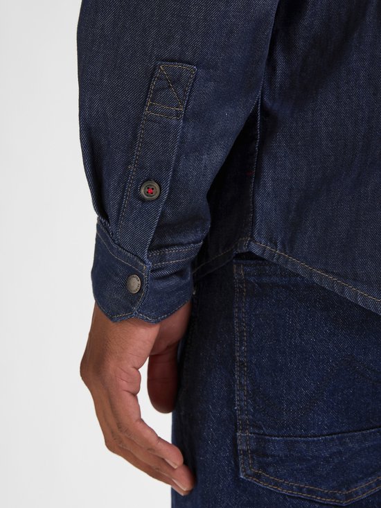 Detail van mouw en knopen van een donkerblauw denim overhemd.