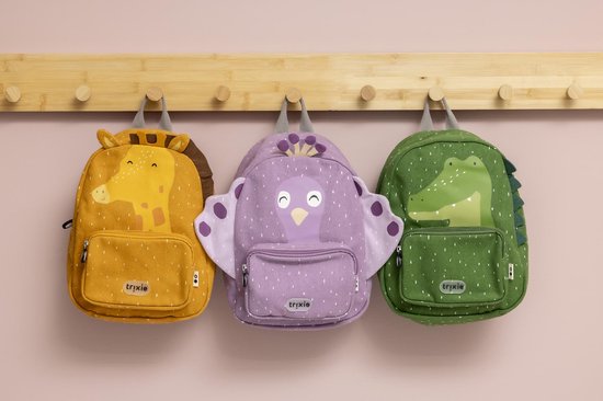 Drie kinderrugzakken hangend aan een rek: een gele giraffe, een paarse pauw en een groene krokodil. Allen met stippenpatroon.