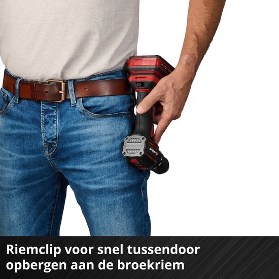 Een man met spijkerbroek en riem, die een rode en zwarte boormachine in zijn broekzak doet met de riemclip.