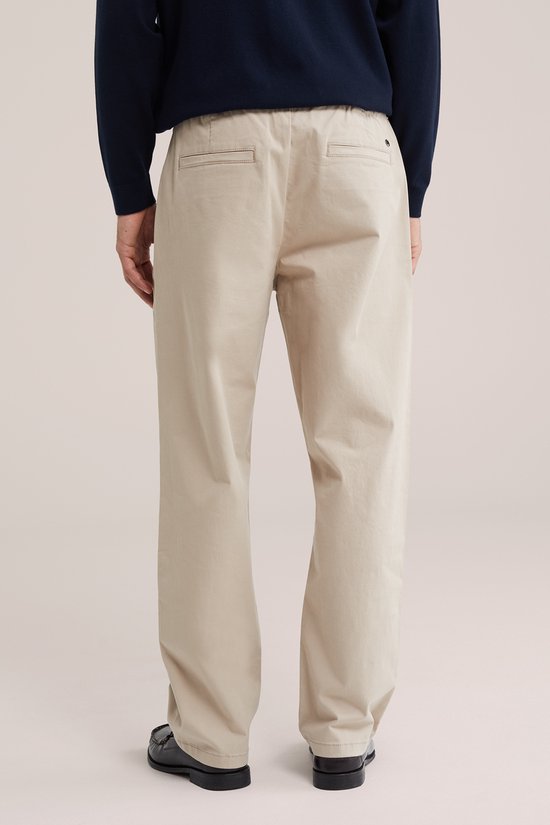 Achterkant van een man in beige wijde broek met elastische tailleband.