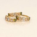 Twee gouden ringen met hartvormige stenen in groen, lichtroze en wit.