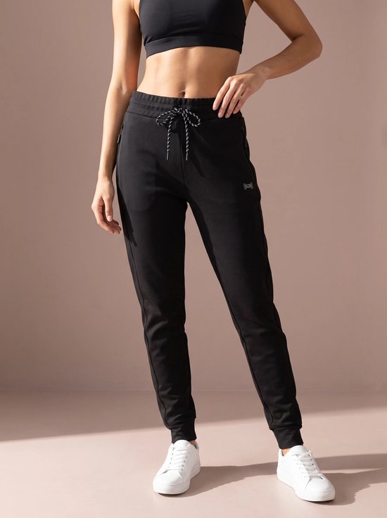 Zwarte sportbroek met trekkoord en witte sneakers, gedragen door een model.