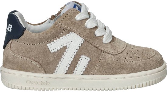 Beige suède sneaker met witte veters, witte 'V' op de zijkant en donkerblauwe hiel.