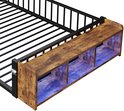 Detail van een zwart metalen kinderbed met houten opbergvak en roze LED-verlichting aan het hoofdeinde.