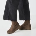 Bruine suède chelsea boots met dikke zool, gedragen door model met zwarte jeans.