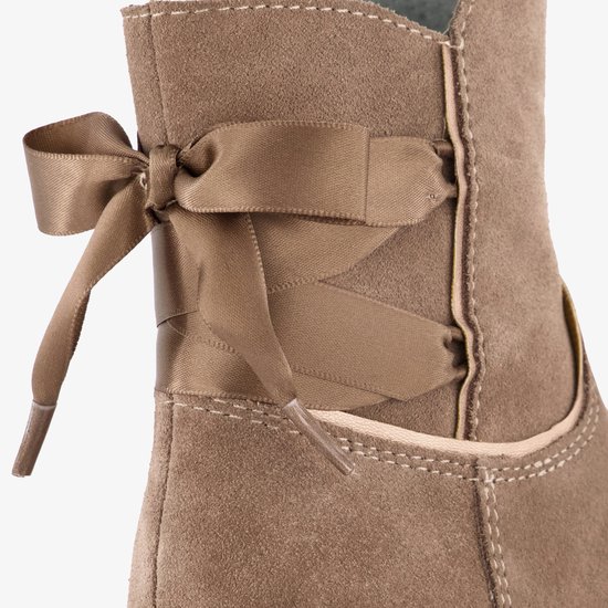 Beige suède enkellaarsjes met aan de achterkant gestrikte strikjes en veters.