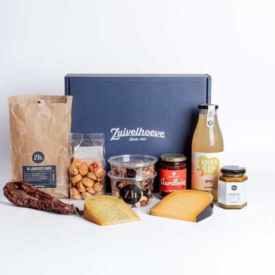 Kerstpakket met kaas, worst, sap, jam, noten en snacks, met de tekst 'Zuivelhoeve' op de doos.