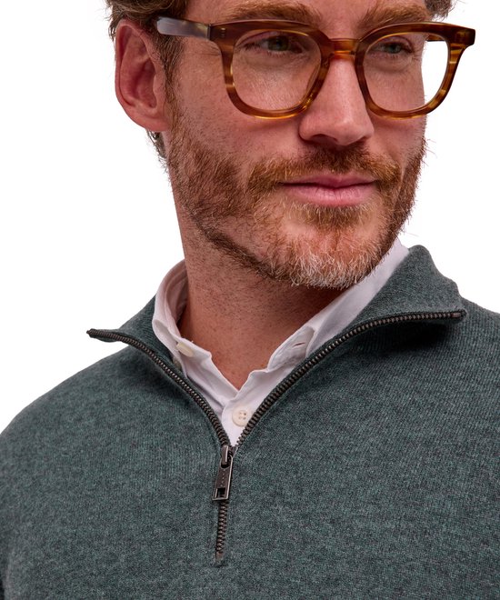 Close-up van een model met een bril en een groene FALKE trui met rits over een wit overhemd.