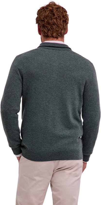 Achteraanzicht van een model in een groene FALKE trui met rits en een beige broek.