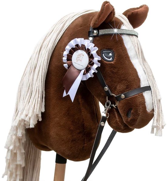 Een bruin stokpaard met een zadel, witte manen, een zwarte teugel en een roos-decoratie met glitters op het hoofd.