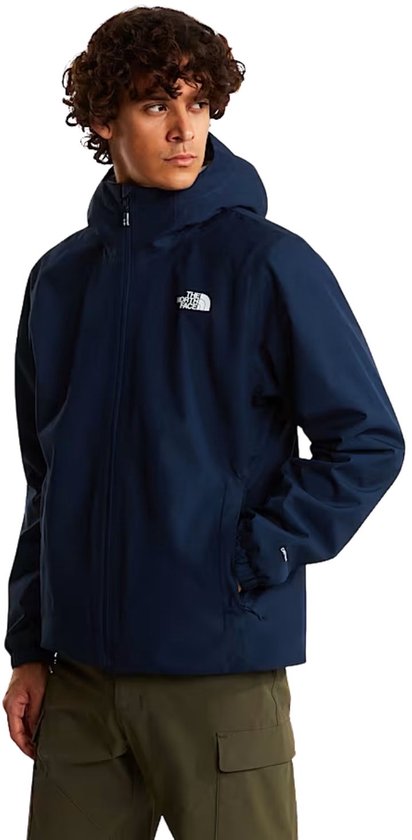 Homme portant une veste bleu marine The North Face. La veste a une capuche et un logo blanc.