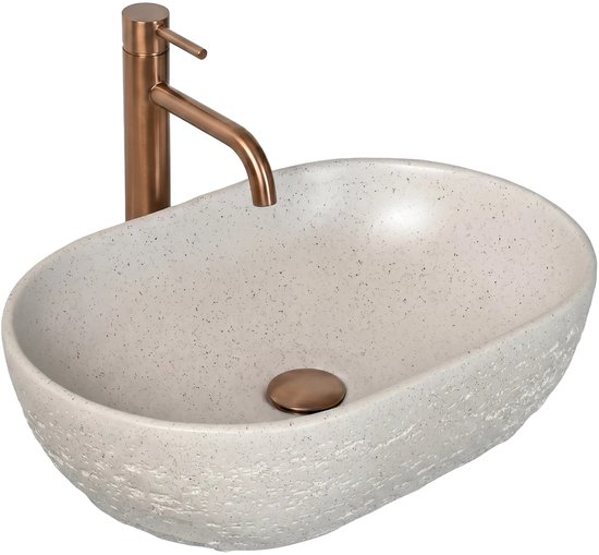 Lavabo ovale gris à surface brute avec bonde et robinet en cuivre.