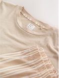 Close-up van de neklijn van een beige T-shirt en de tailleband van een short met verticale strepen.
