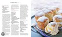 Een stapel zachte witte broodjes met poedersuiker, waarvan er één is doorgesneden en gevuld met gele crème en poedersuiker.