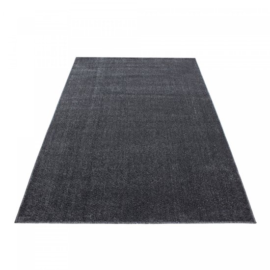 Un tapis uni gris foncé à poils courts, à plat sur un fond blanc.