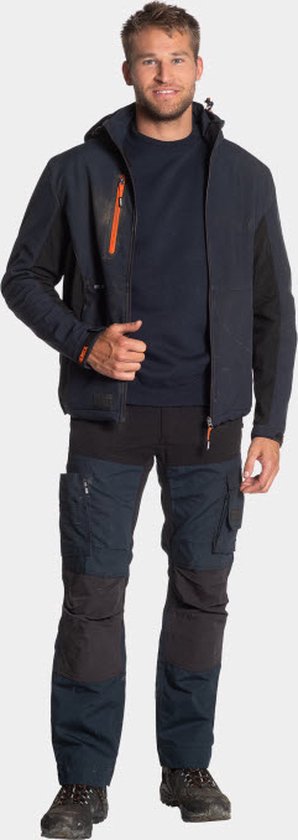 Man in een donkerblauwe Herock softshell werkjas, met een donkerblauwe trui en werkbroek.