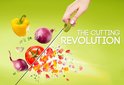 Een hand die een groene snijhulp vasthoudt, boven zwevende gele paprika, rode ui, tomaat en knoflook, met de tekst "THE CUTTING REVOLUTION".