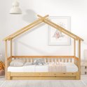 Houten huisbed met matras, kussens en een deken, met een sprookjesachtige print aan de muur.