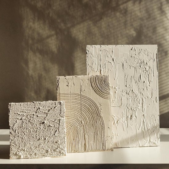 Drie witte textuurkunstwerken met verschillende reliëfs en texturen op een witte ondergrond.