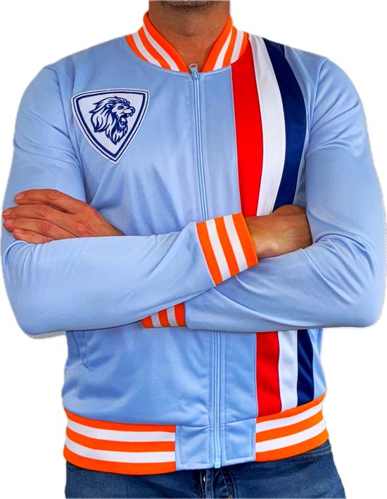 Man met lichtblauwe retro trainingsjas, voorzien van oranje, witte en marineblauwe strepen en leeuw embleem op de borst.