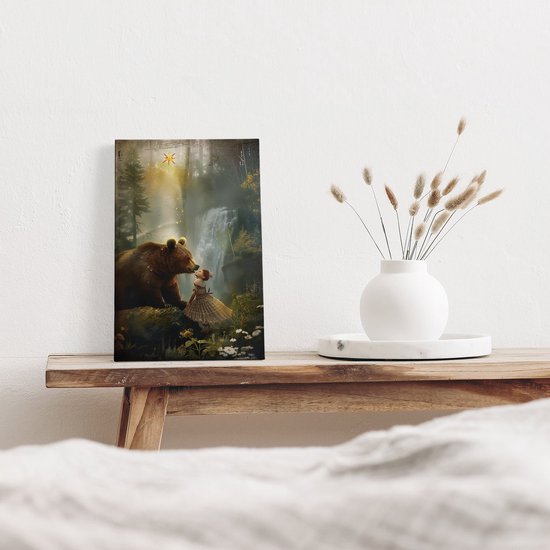 Une peinture d'un ours et d'une fille dans une forêt avec une cascade, placée sur un meuble.