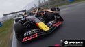 Een zwarte en rode Formule 1 auto met gele accenten racet op een nat circuit, met een oranje auto naast.