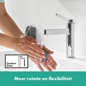 Close-up van een vrouw die haar handen wast onder een glanzende chroom kraan met tekst 'Kristalheldere stroom'.