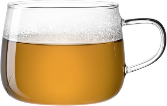 Een doorzichtig glazen mok, voor de helft gevuld met amberkleurige thee, tegen een witte achtergrond.